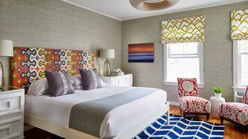 A bedroom with a bed, nightstands, a chair, a rug, and a window with curtains.