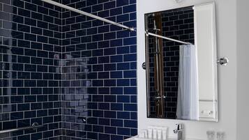 Ein modernes Badezimmer mit Dusche, einem weißen Waschbecken und einem Spiegel.