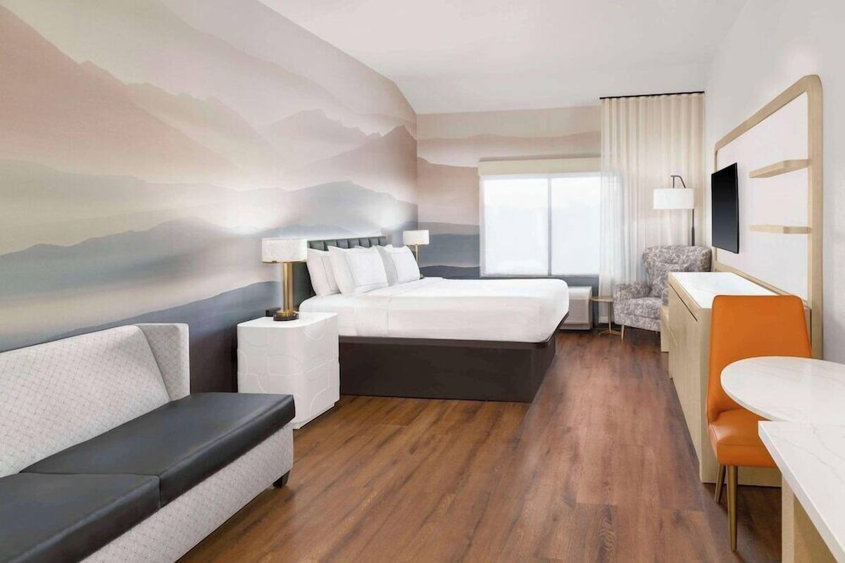 A hotel room with a bed, a sofa, a desk, and a chair.