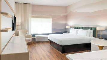 A hotel room with a bed, a desk, a chair, a TV, and a window with curtains.