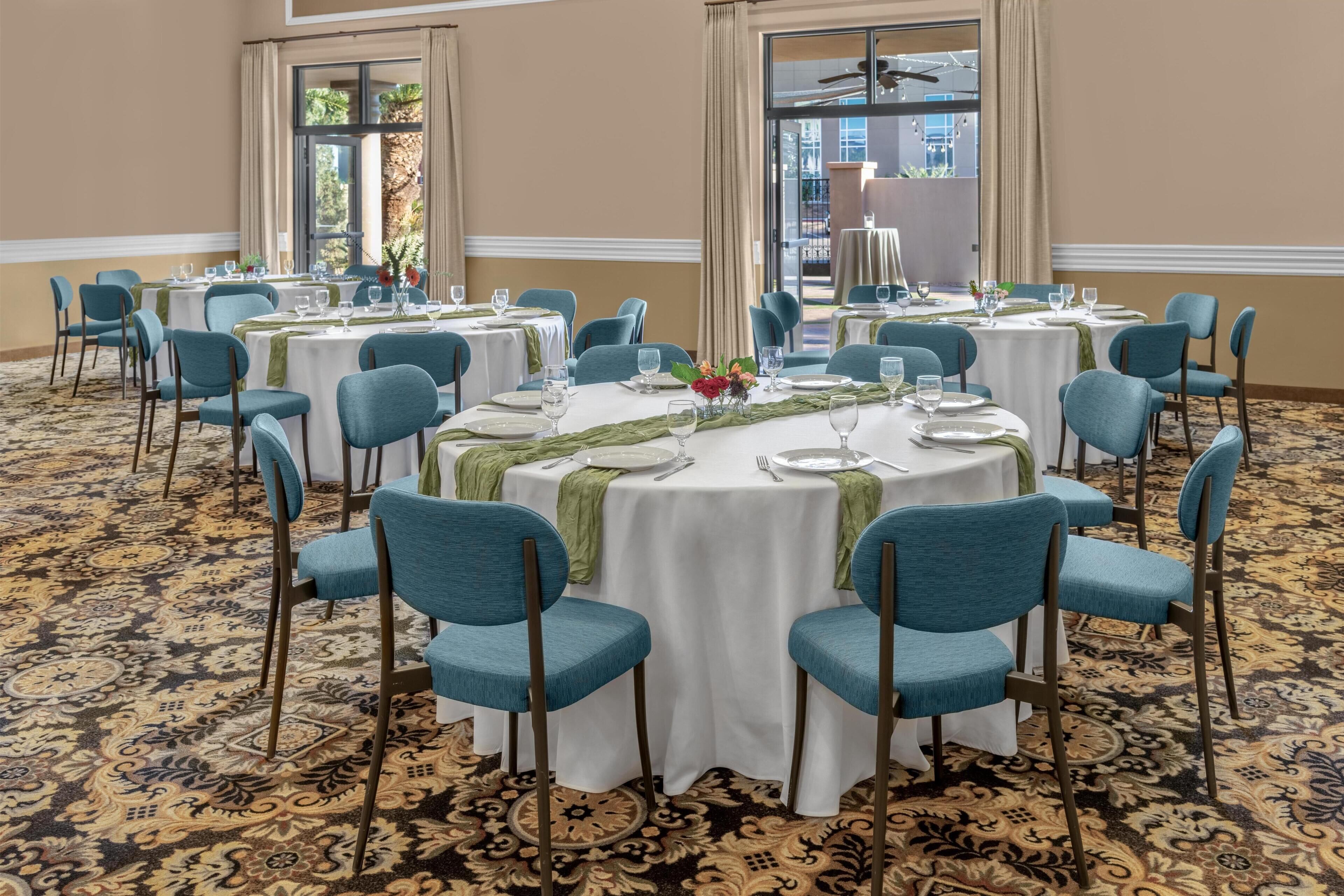 A conference room with round tables, blue chairs, and a patterned carpet.