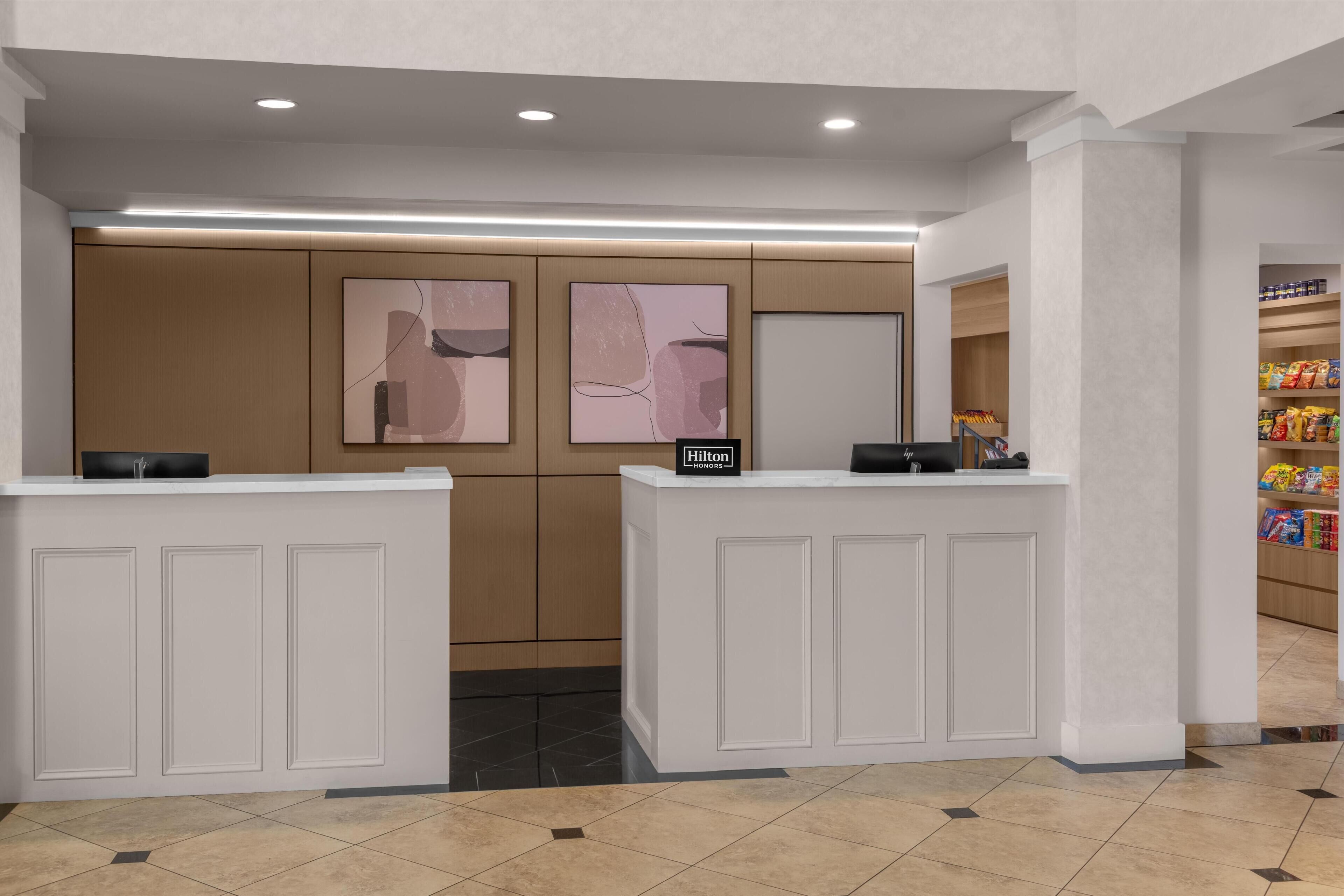 A hotel reception area with two counters, a modern design, and a visible Hilton sign.
