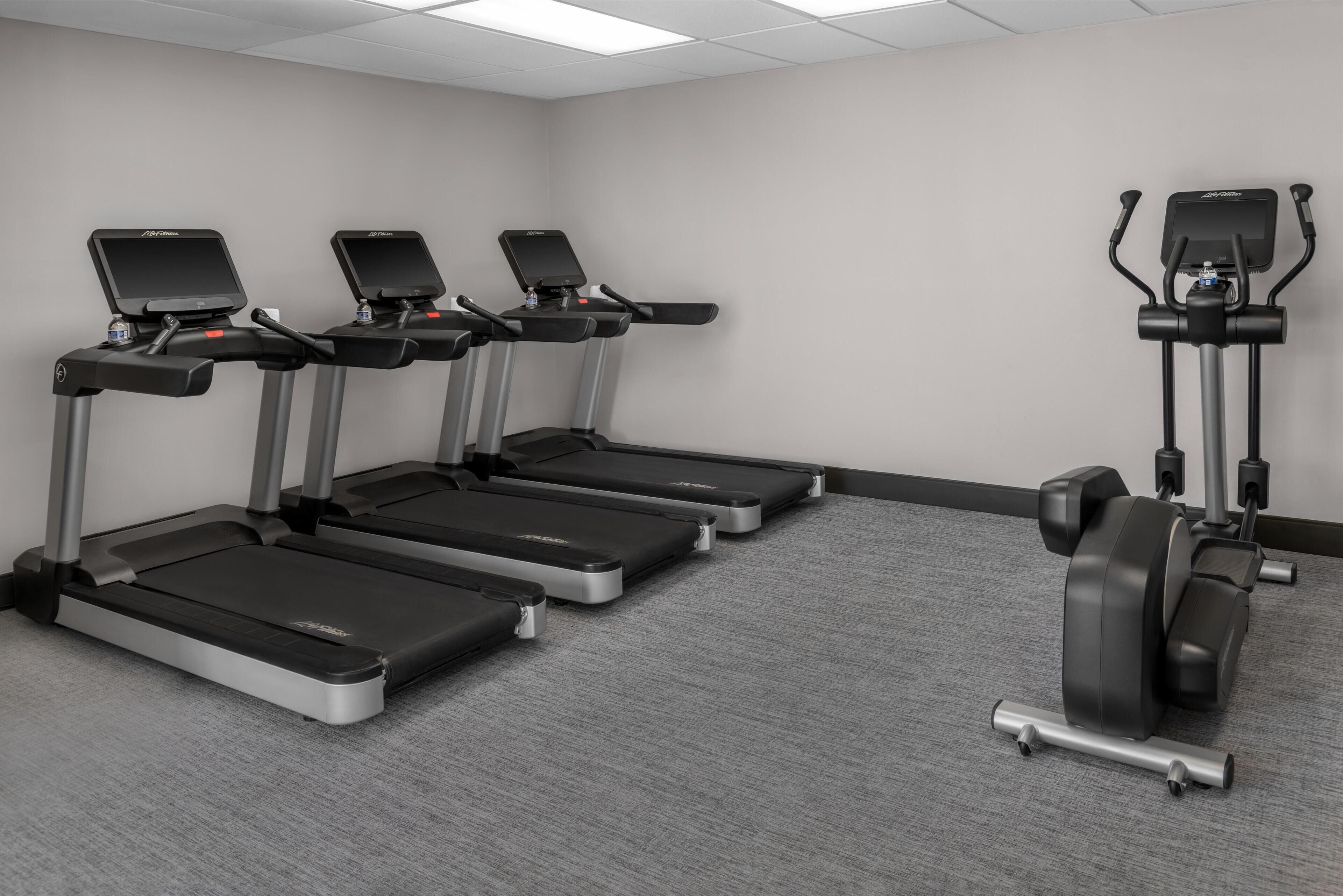 A gym with treadmills, a stationary bike, and a weight bench.