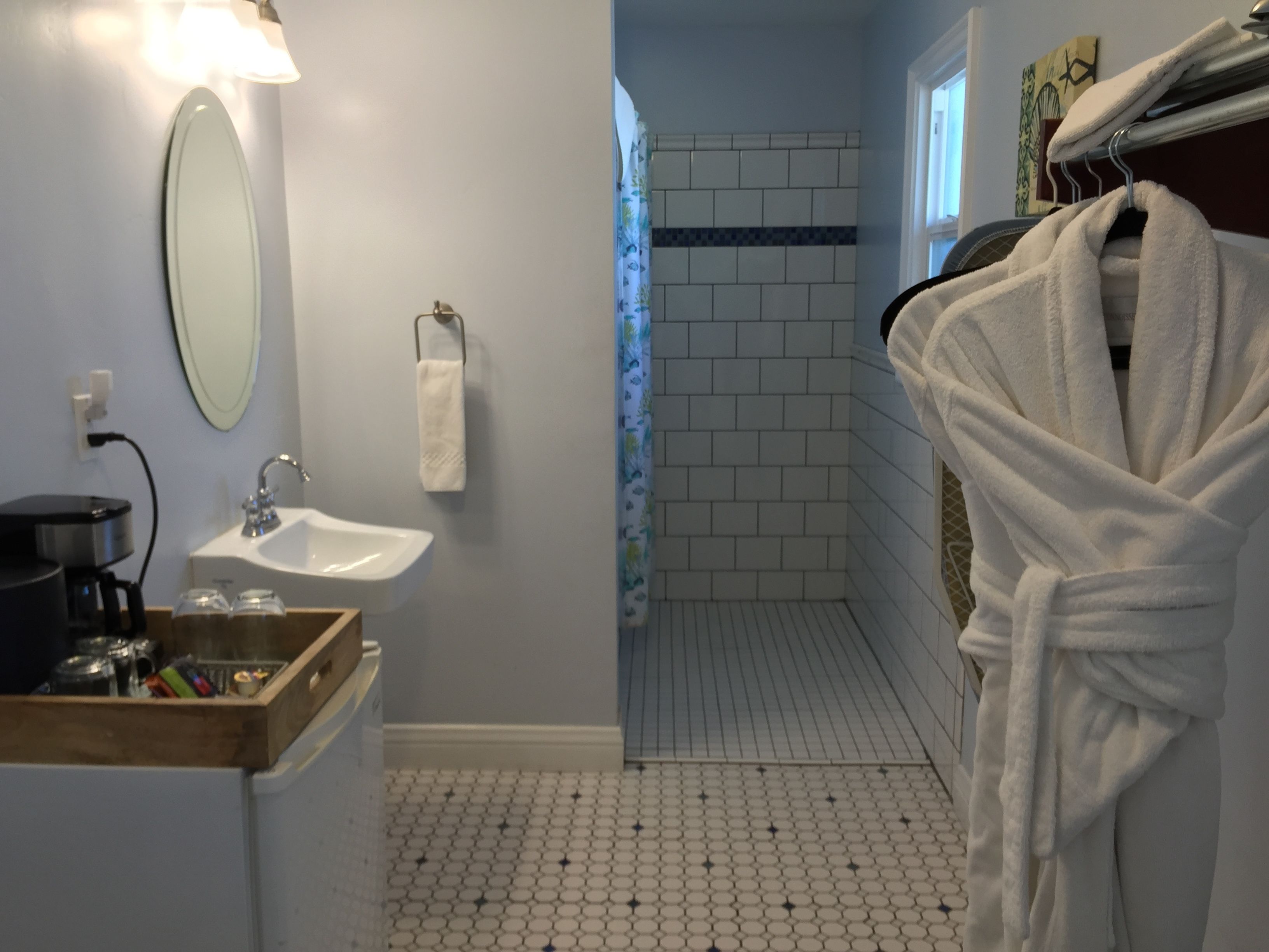 A bathroom with a sink, mirror, towel rack, and a robe hanging on a rack.
