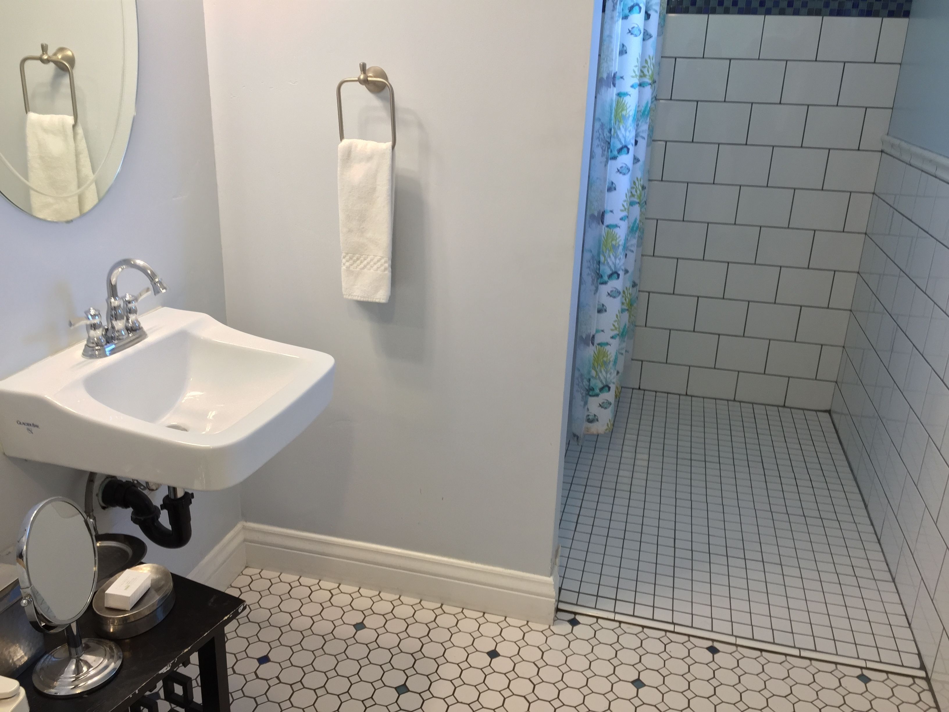 A bathroom with a white sink, a mirror, and a shower curtain with a fish pattern.