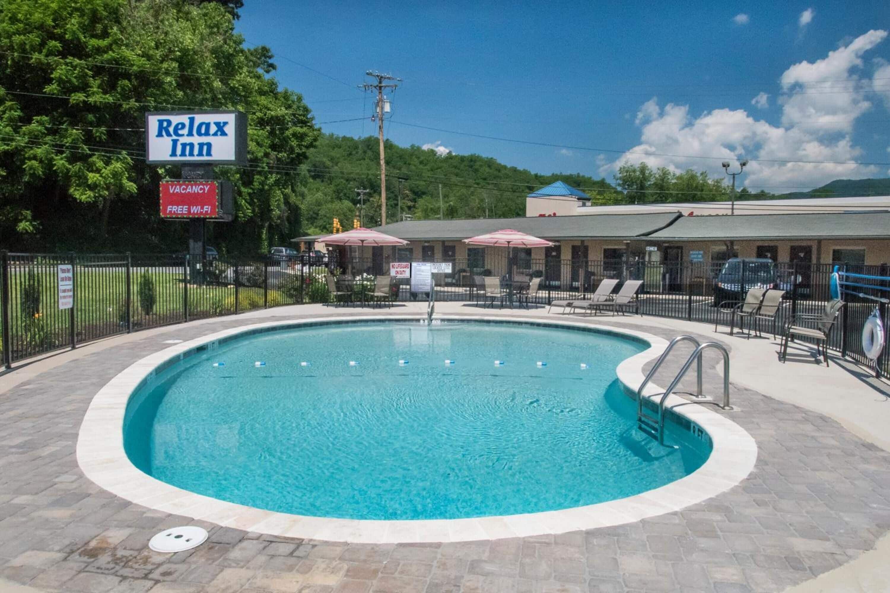 Une zone avec piscine, sur laquelle on peut voir une enseigne indiquant « Relax Inn » et une autre indiquant « Chambres disponibles ».