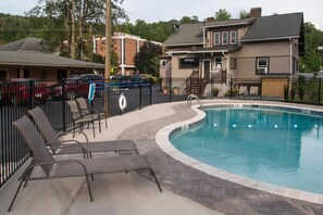 A swimming pool with lounge chairs and a lifeguard stand, surrounded by a fence and a brick walkway. - Relax Inn (Bryson City)
