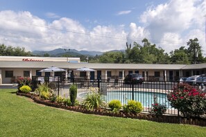 A motel with a swimming pool, outdoor seating, and a mountain backdrop. - Relax Inn (Bryson City)