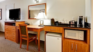 A hotel room with a wooden desk, a television, a lamp, a microwave, a coffee maker, and a mini-fridge. - Canalta Hotel Jurassic – Drumheller (Drumheller)