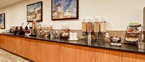 Un buffet de petit-déjeuner d’hôtel avec un comptoir en bois, des machines à café et divers aliments.
