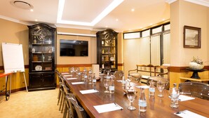 A conference room with a long wooden table, chairs, a whiteboard, and a television on the wall. - Coopmanhuijs Boutique Hotel (Stellenbosch)