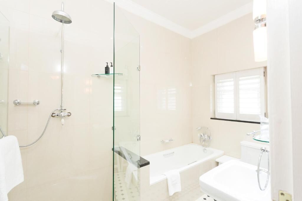 A modern bathroom with a glass-enclosed shower, a freestanding bathtub, and a glass-enclosed vanity with a toilet.