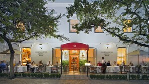 The exterior of the Coopmanhuis Hotel with outdoor seating and a red awning. - Coopmanhuijs Boutique Hotel (Stellenbosch)