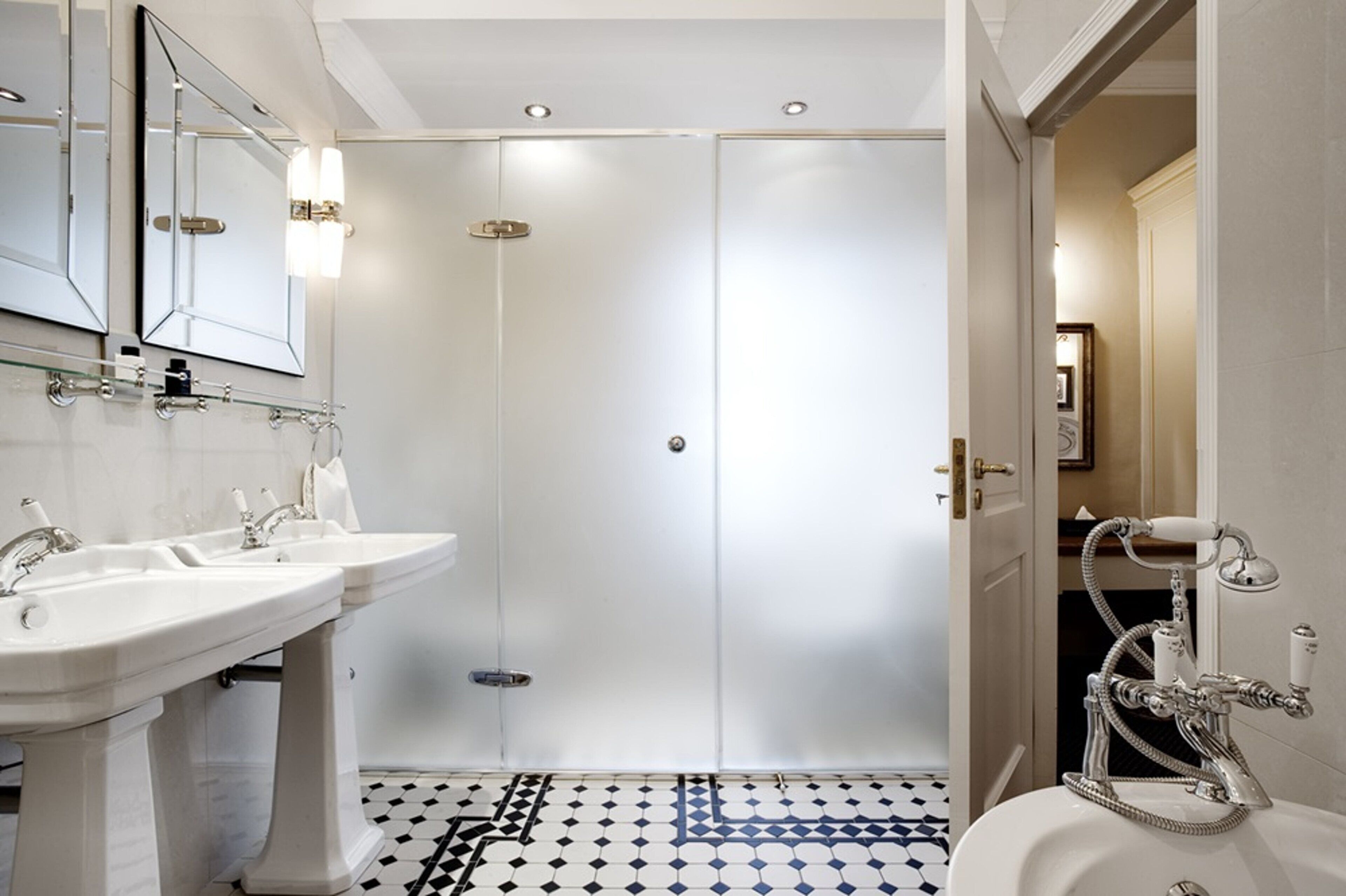 A bathroom with two sinks, a mirror, and a shower with a hose.