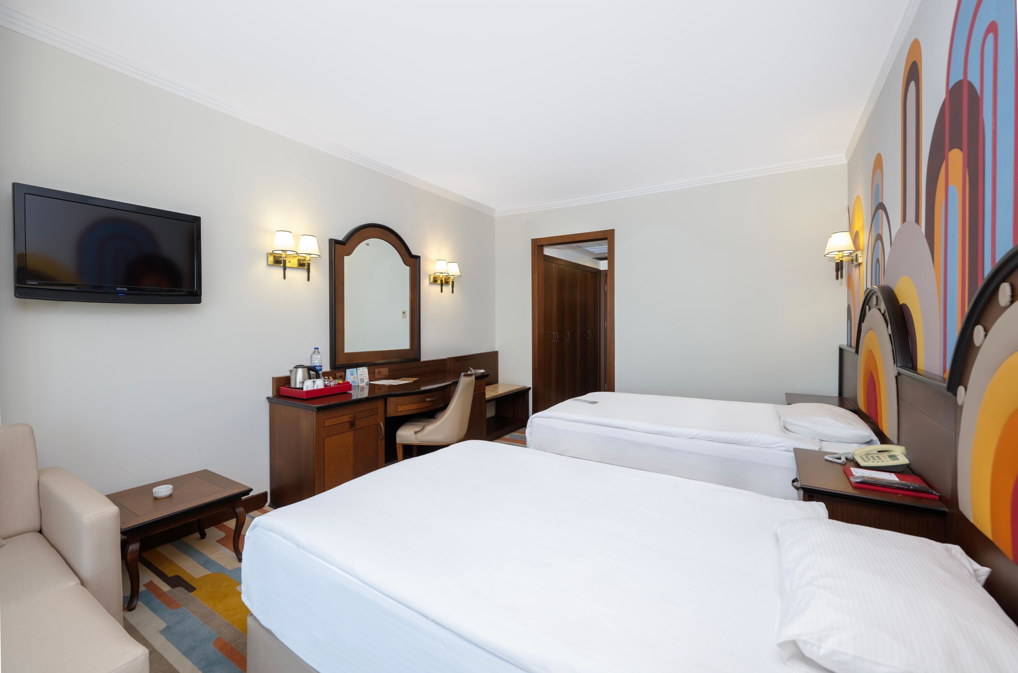 Een hotelkamer met twee bedden, een bureau, een stoel, een televisie en een badkamers deur.