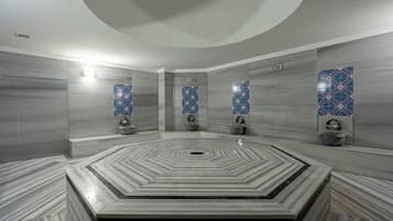 A modern bathroom with a central circular sink, marble flooring, and decorative tile walls.