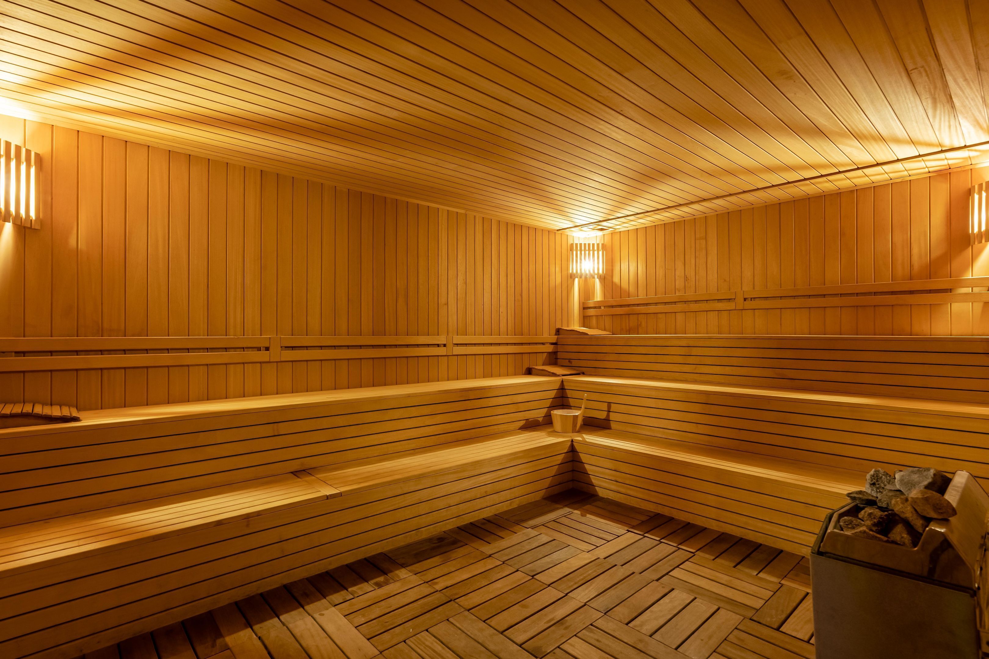 Eine Sauna mit Holzbänken und -wänden, einem Holzboden und einem Mülleimer.