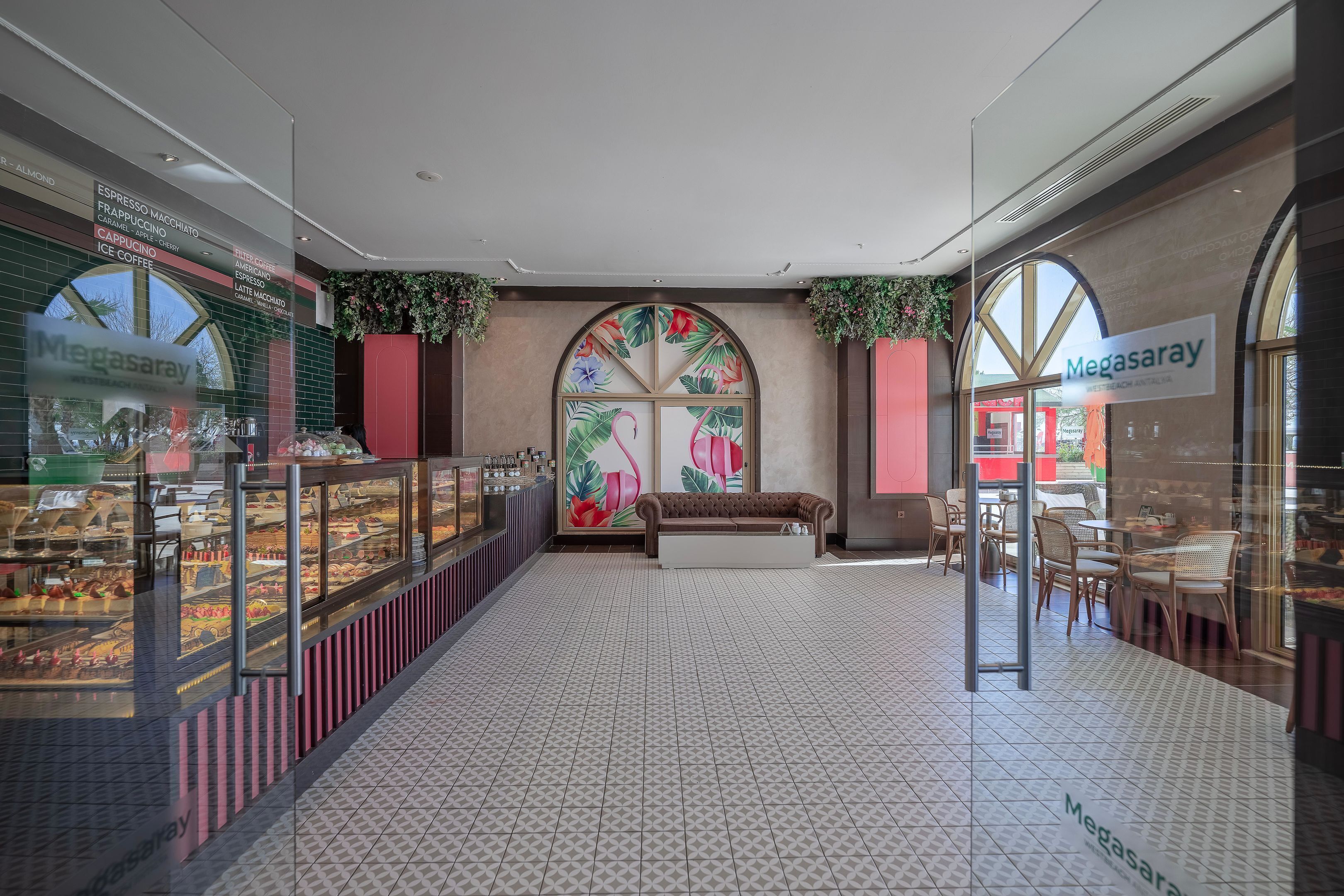 A spacious indoor area with a tiled floor, a seating area with a sofa, and a display case with various food items.