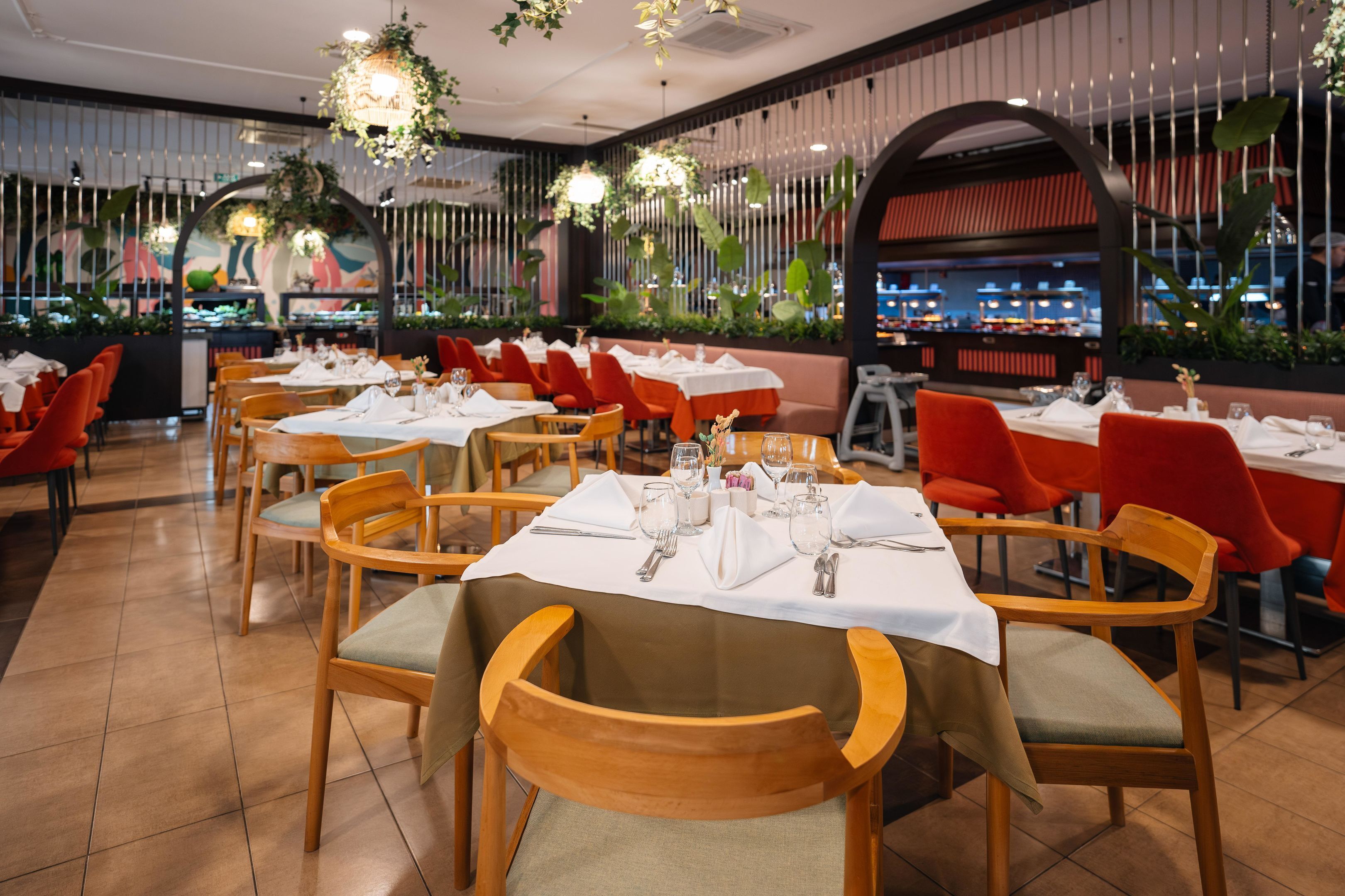 A restaurant with multiple tables set for dining, featuring wooden chairs and a modern interior design.