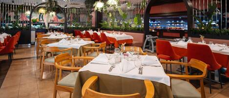 A restaurant with multiple tables set for dining, featuring wooden chairs and a modern interior design.