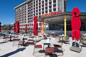 Un hotel con área de comedor al aire libre, sombrillas rojas y un cartel que dice "megafood".
