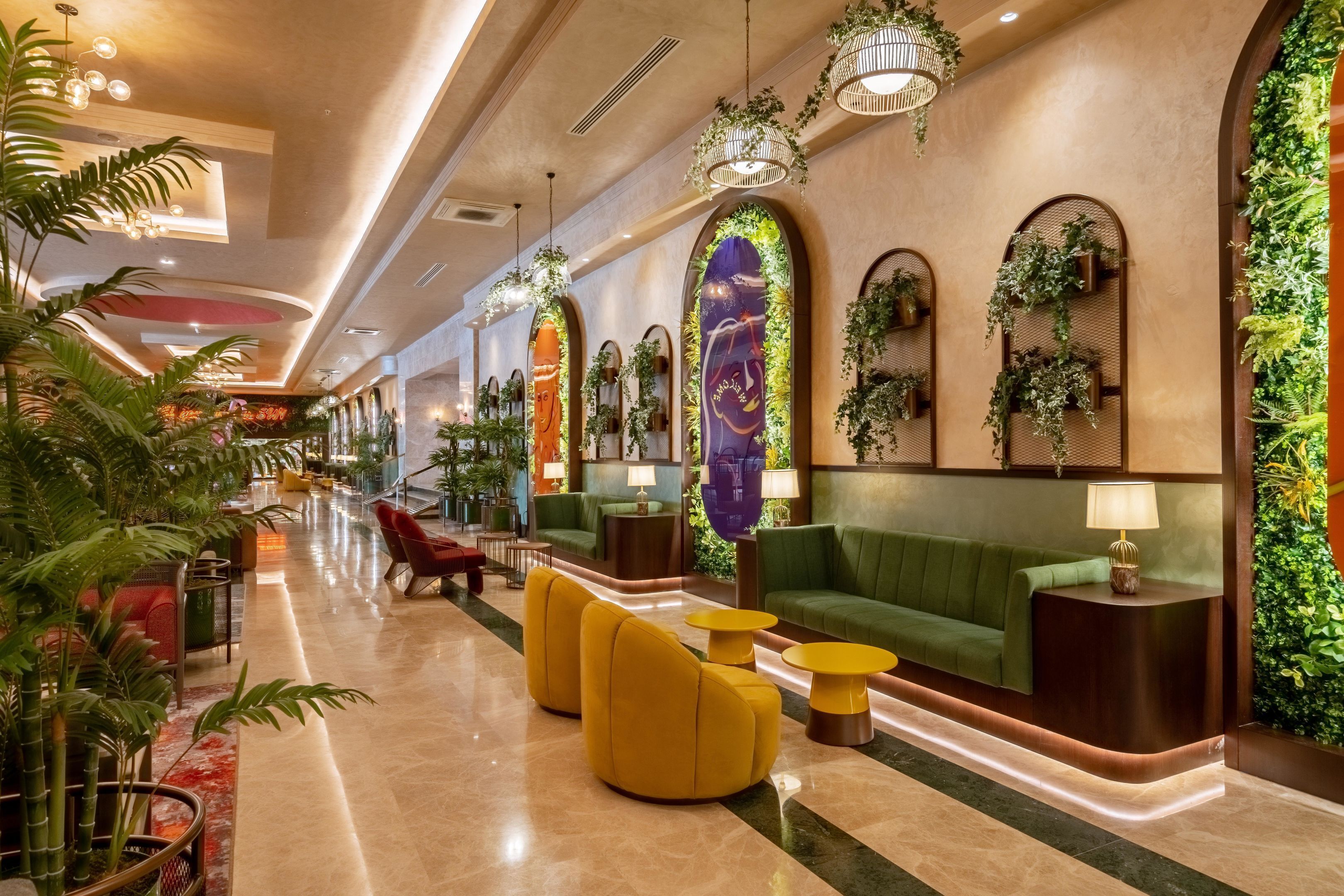 Un hall d’entrée moderne avec un canapé vert, des fauteuils jaunes et un comptoir d’accueil.