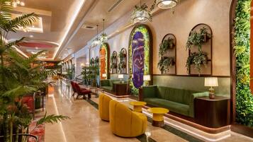Un hall d’entrée moderne avec un canapé vert, des fauteuils jaunes et un comptoir d’accueil.