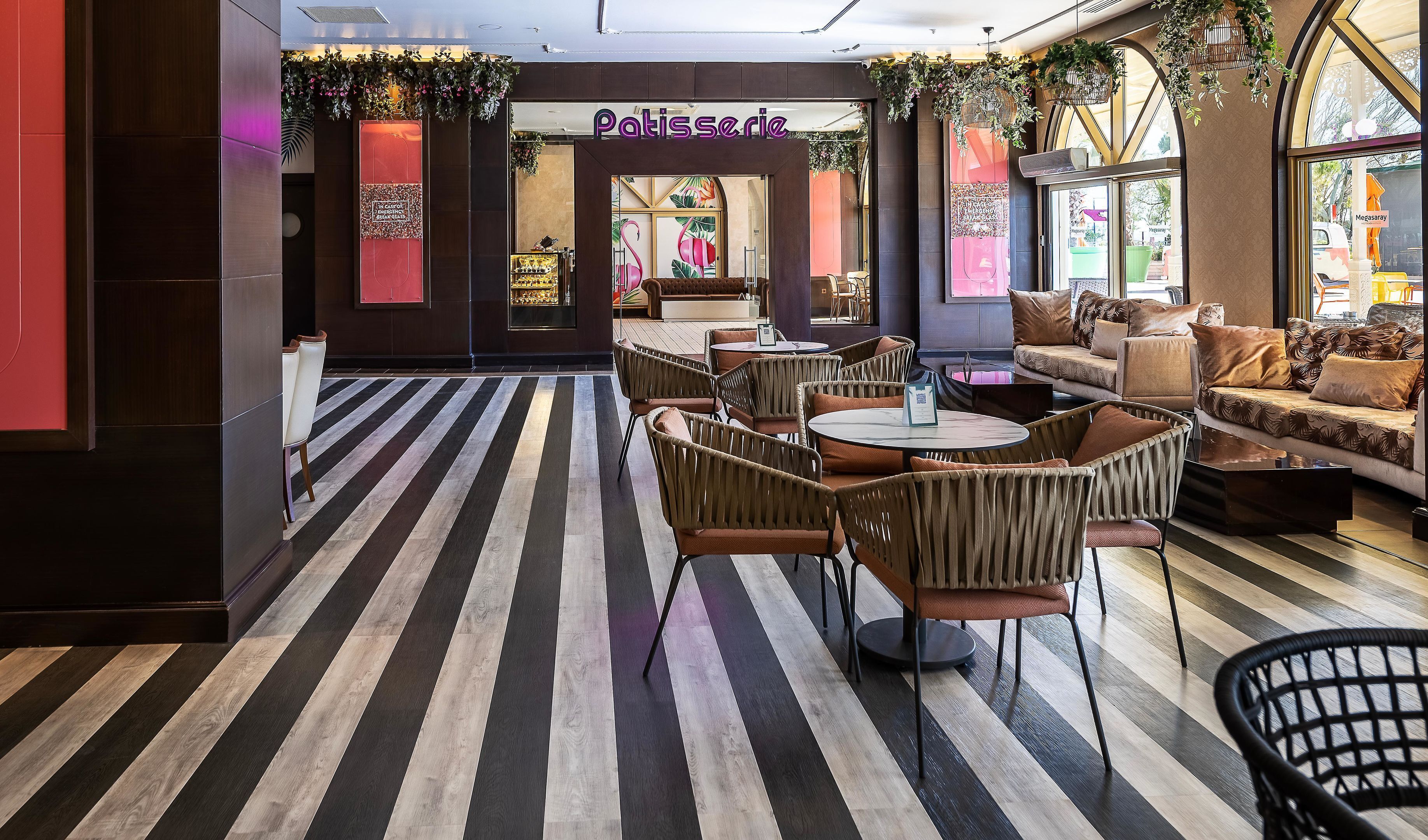L’intérieur d’un café moderne, avec un sol à rayures, des meubles en osier et une enseigne indiquant « Pâtisserie ».