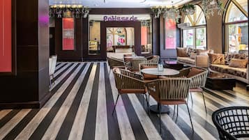 L’intérieur d’un café moderne, avec un sol à rayures, des meubles en osier et une enseigne indiquant « Pâtisserie ».
