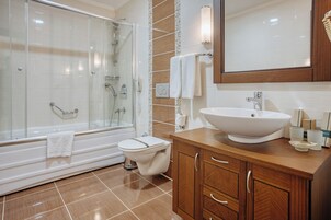 A modern bathroom with a glass-enclosed shower, a white sink, and wooden cabinetry.