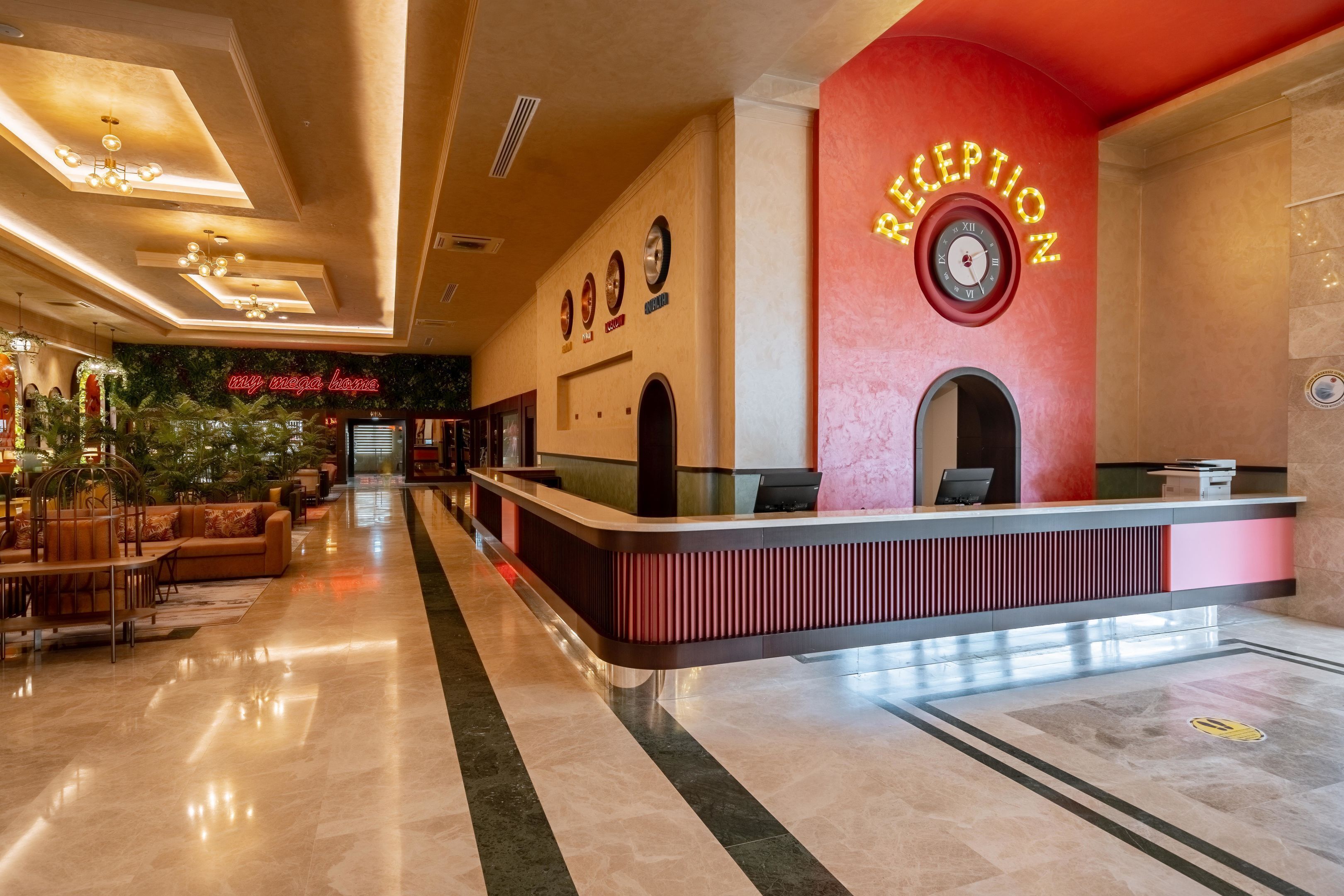 Zona de recepción de hotel con diseño moderno, que incluye un mostrador de recepción, un reloj y un letrero de neón.