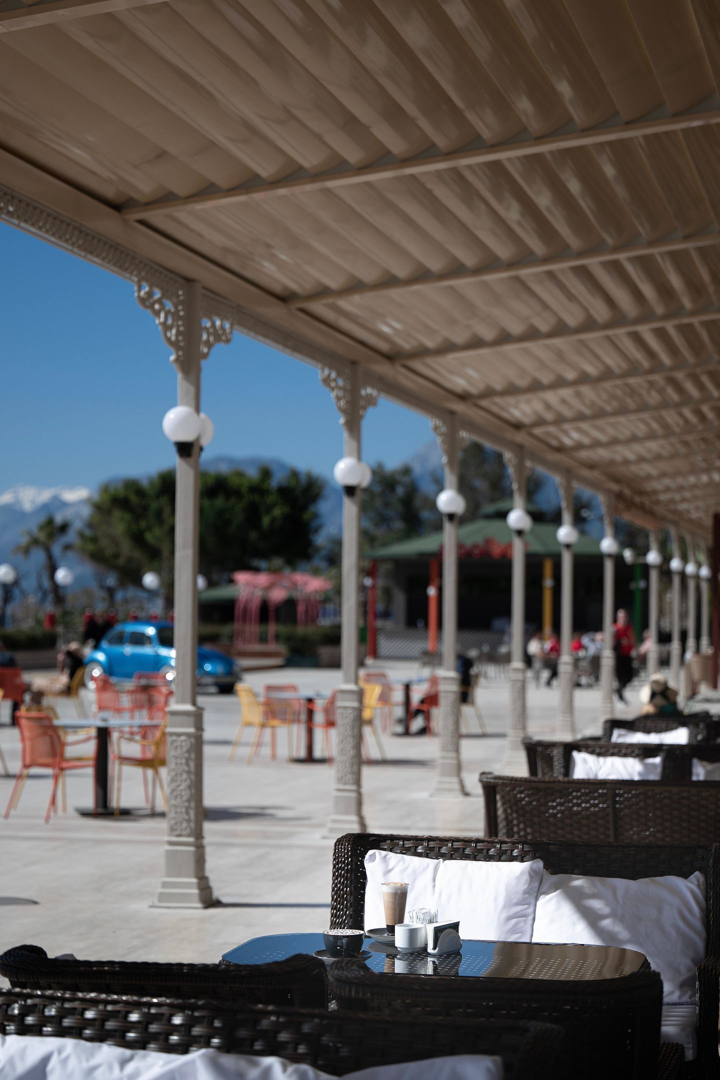 A covered outdoor seating area with wicker furniture and a table with a cup and saucer.