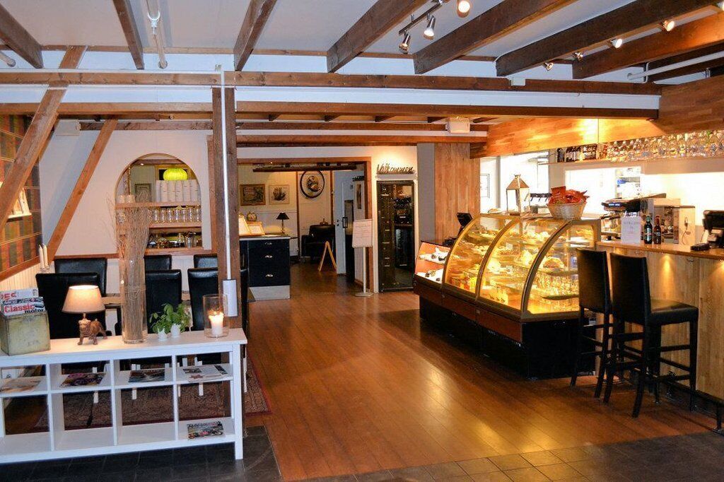 A cozy interior with a wooden ceiling, a glass display case with pastries, and a bar area.