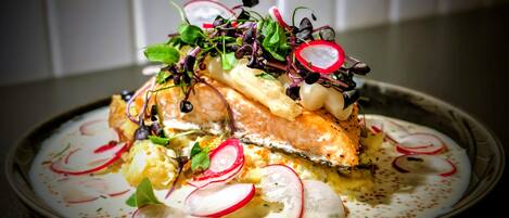 Um prato com salmão, rabanetes e folhas verdes.