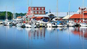 Un puerto deportivo con varias embarcaciones amarradas, edificios rojos y agua tranquila.