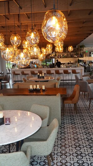 A restaurant interior with round tables, chairs, and hanging spherical light fixtures. - Hotel Estelar El Cable (Manizales)