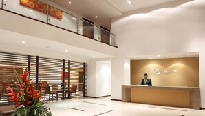 A modern hotel lobby with a reception desk, seating area, and a decorative plant. - Hotel Estelar El Cable (Manizales)