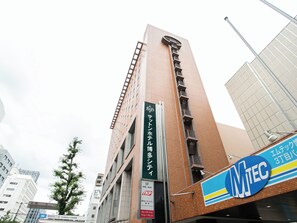 A tall building with a sign for a hotel on the side. - Sutton Hotel Hakata City (Fukuoka)