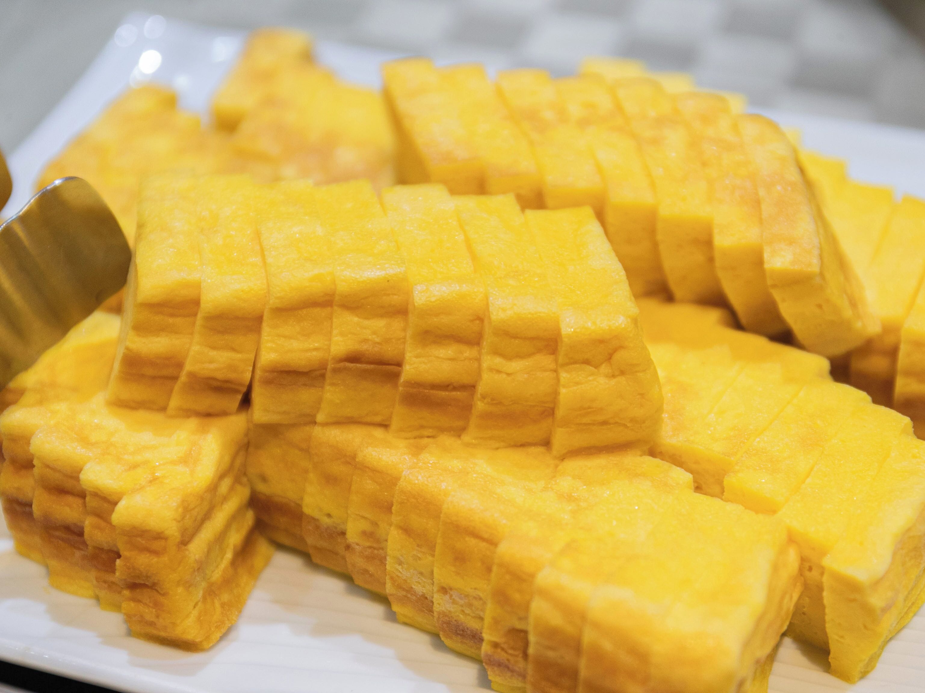 A white plate with neatly cut yellow mango chunks.