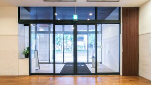 A modern entrance with a glass door, a black mat, and a ceiling light. - Sutton Hotel Hakata City (Fukuoka)