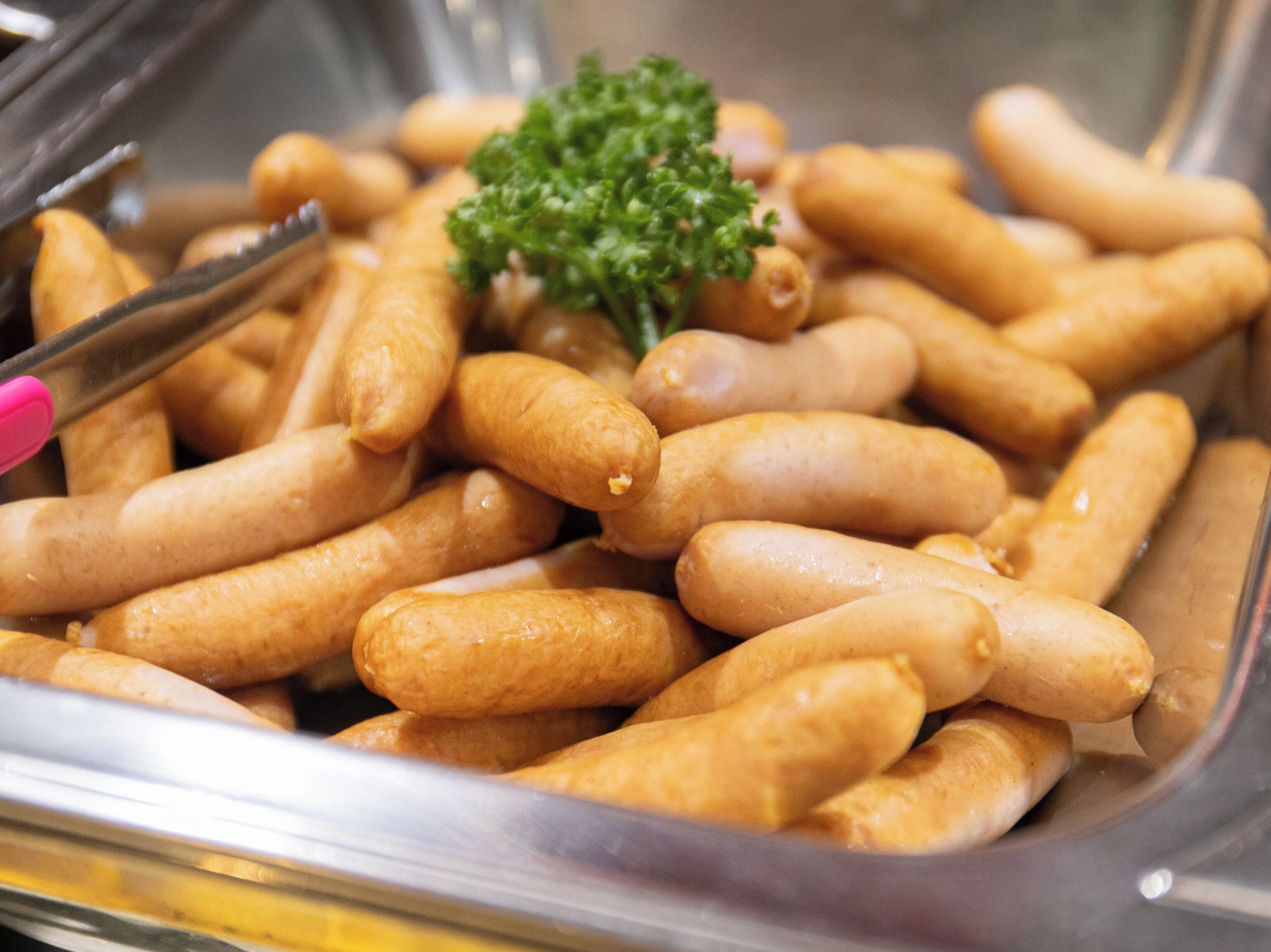 A tray of golden-brown sausages garnished with parsley.
