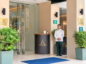 A reception area with a glass door entrance, a reception desk, and a sign indicating the Central Embassy.