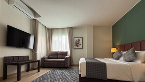 A hotel room with a bed, a sofa, a TV, and an air conditioning unit. - The Legacy Hotel Nana Sukhumvit, Aspira Collection (Bangkok)