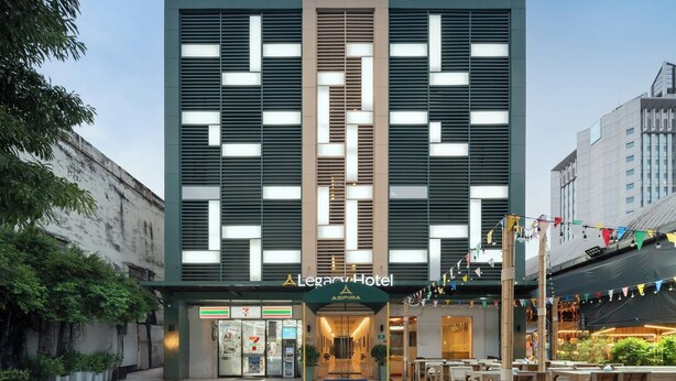 The exterior of the Legacy Hotel with a modern design, featuring a prominent entrance and a 7-Eleven convenience store on the ground floor. - The Legacy Hotel Nana Sukhumvit, Aspira Collection (Bangkok)