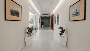 A modern hallway with framed pictures on the walls, potted plants, and a clean, tiled floor. - The Legacy Hotel Nana Sukhumvit, Aspira Collection (Bangkok)