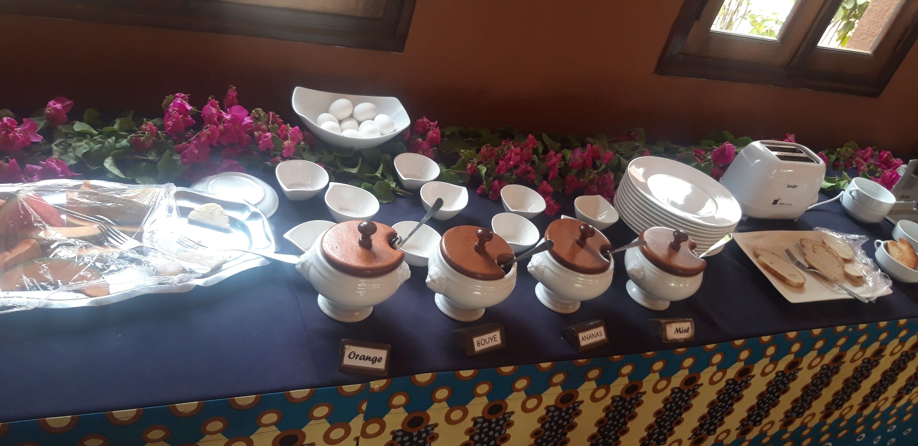 Een buffet tafel met diverse soorten eten en bestek, waaronder kommen met aanduidingen zoals 'Orange' en 'Bouye'.