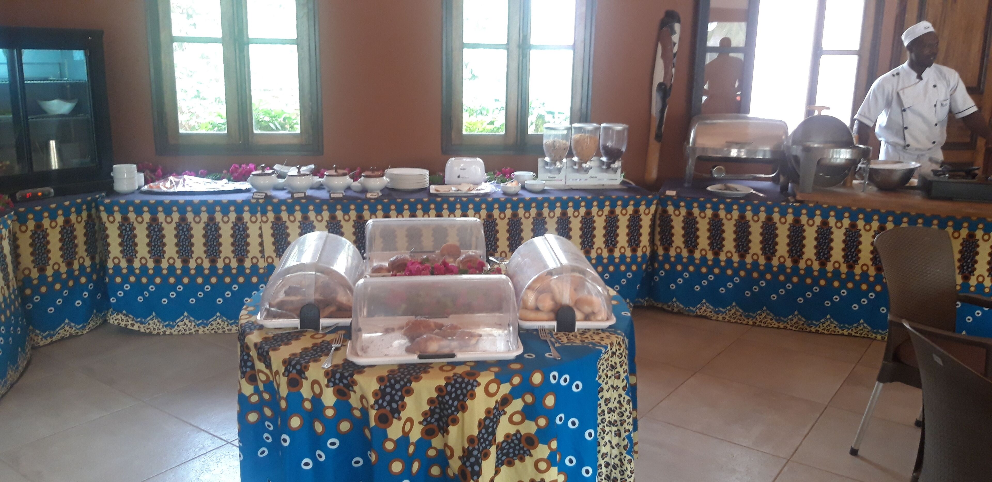 A buffet setup with covered food displays and a chef preparing food.