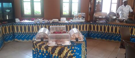 A buffet setup with covered food displays and a chef preparing food.