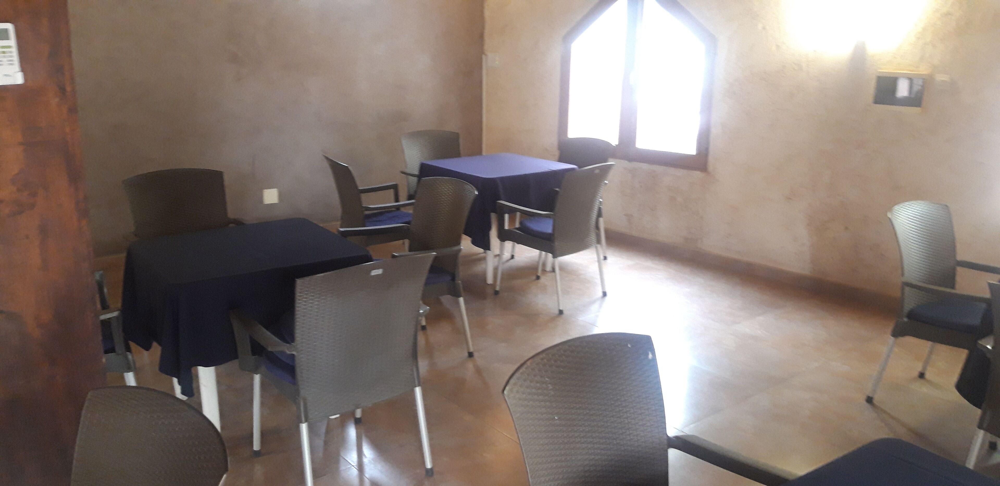 A room with a table and chairs, a window, and a wall-mounted light fixture.