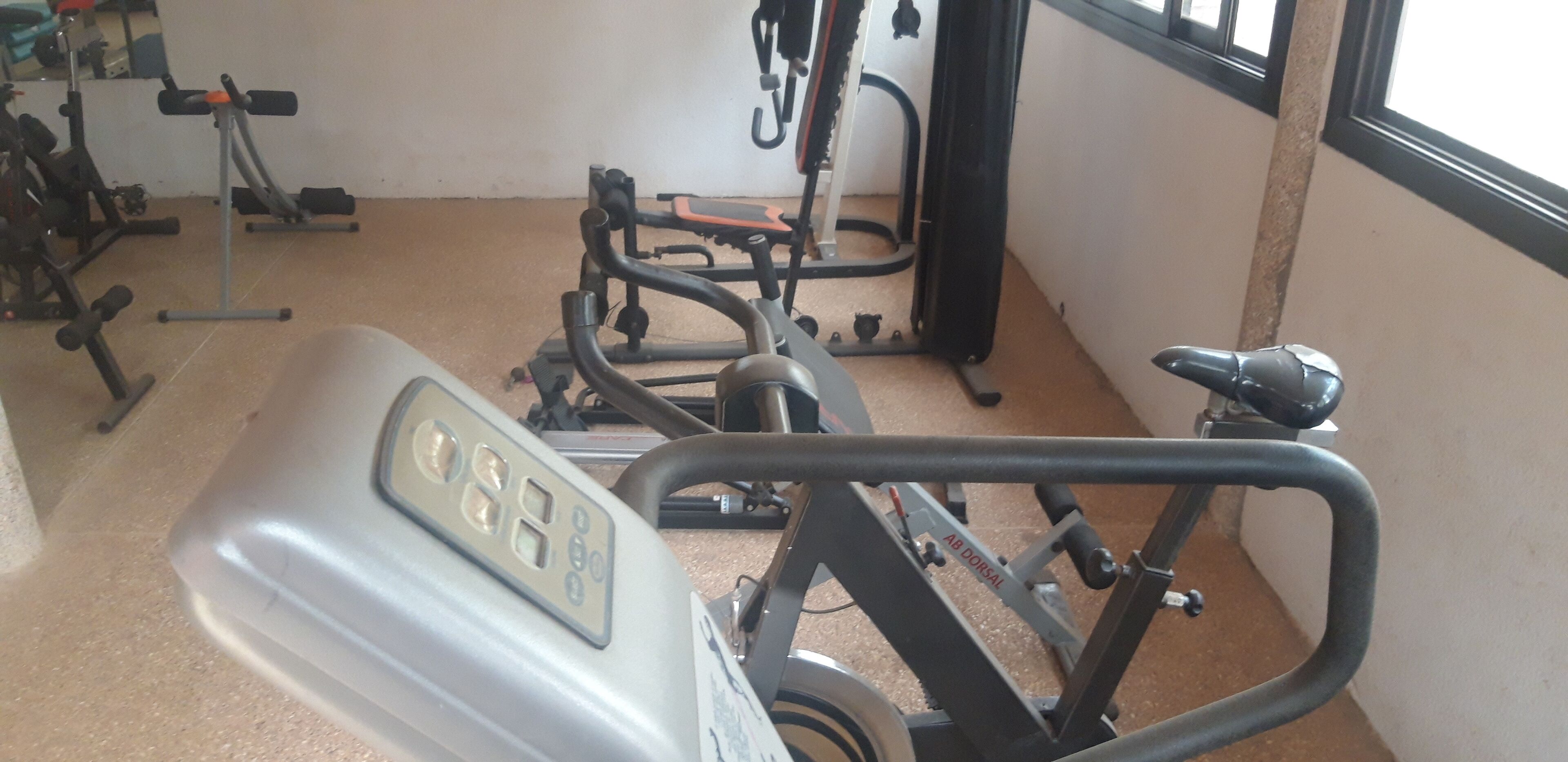A gym with exercise equipment including a stationary bike, a rowing machine, and weightlifting machines.